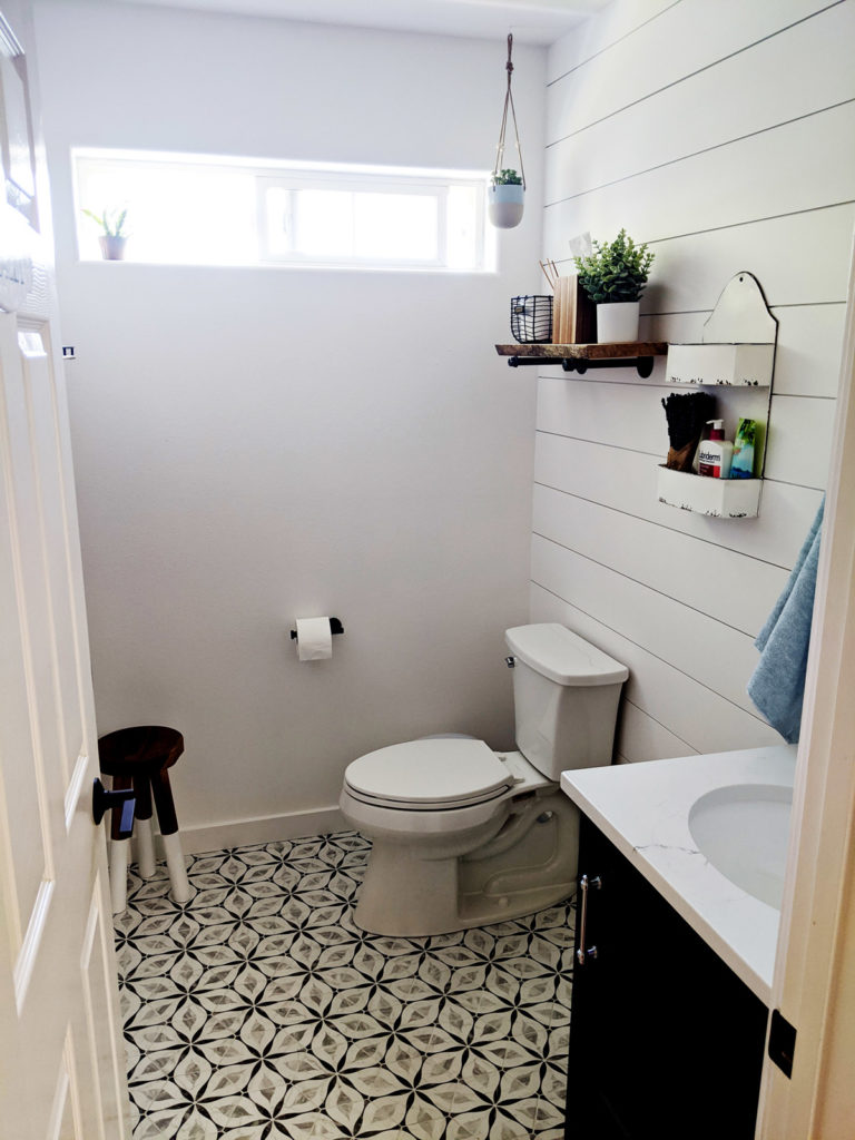 freshly remodeled bathroom with a black and white high-contrast tile floor and coped and painted shiplap on the walls.